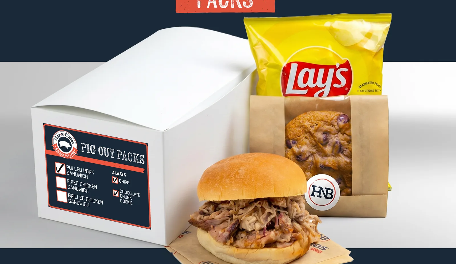 Hog-N-Bones Pig Out Packs boxed lunch with the checklist label on the box, pulled pork sandwich, chips, and cookie